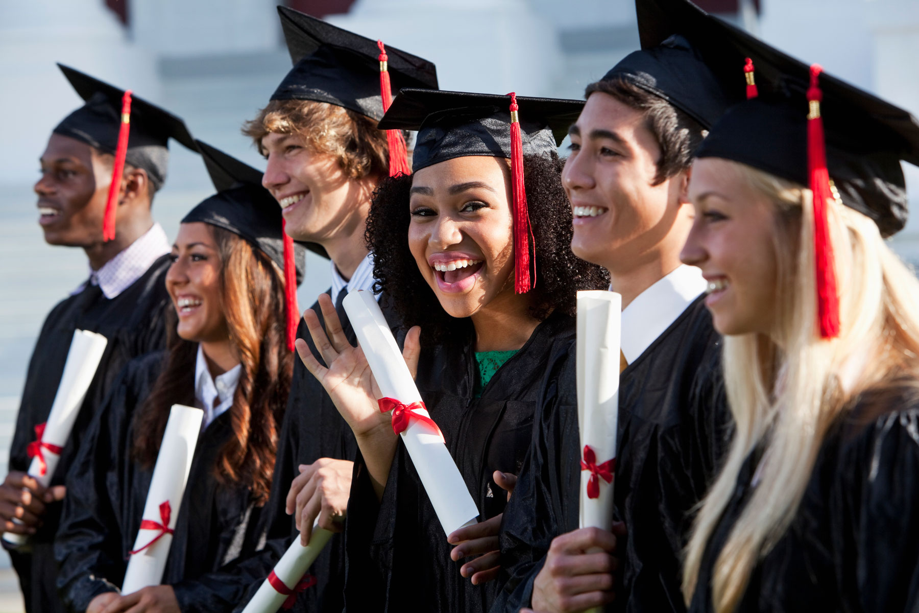 happy, diverse college students at graduation ceremony