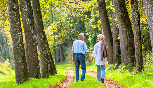 Seniors walking happily along path in woods
