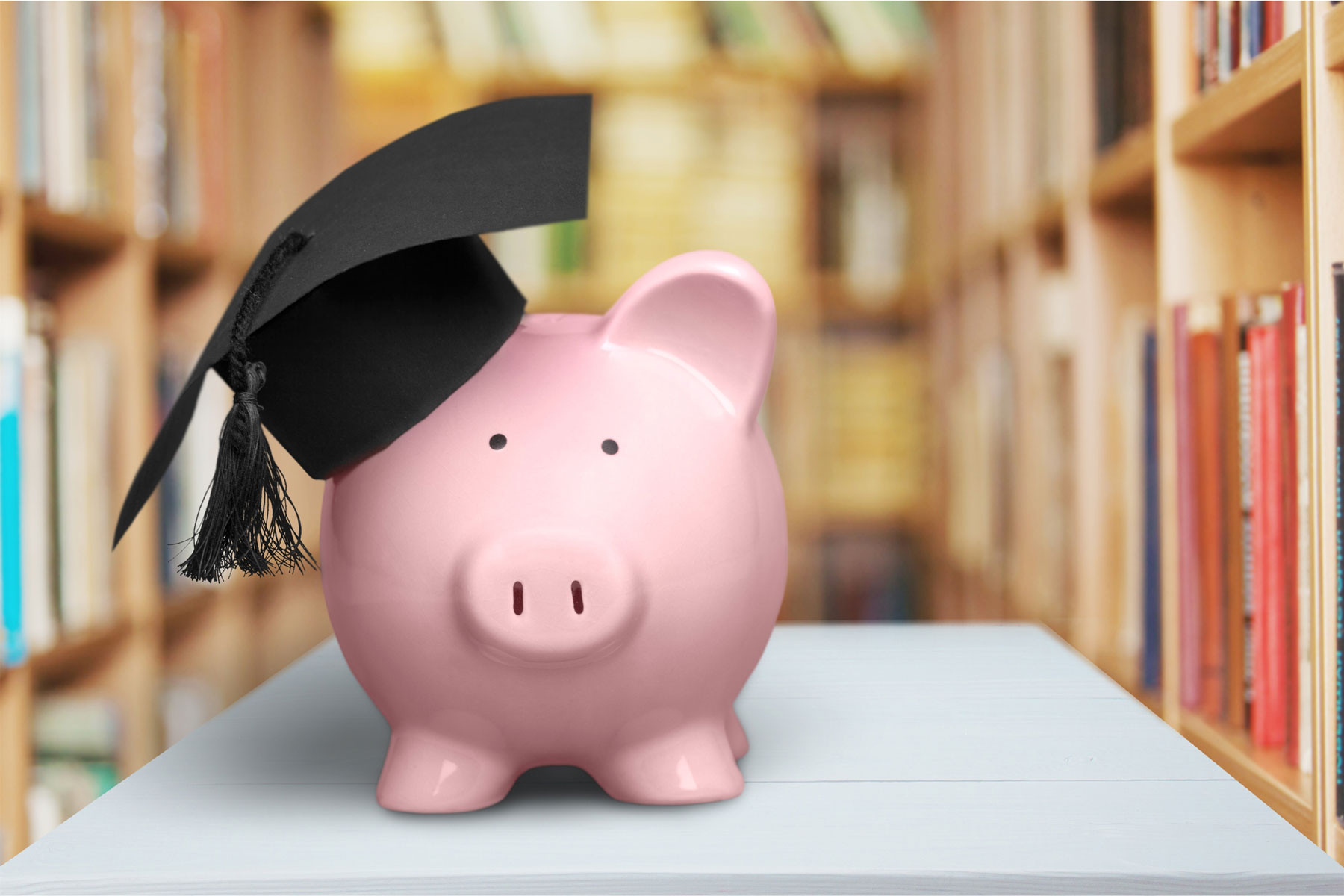 piggy bank with graduation cap in library