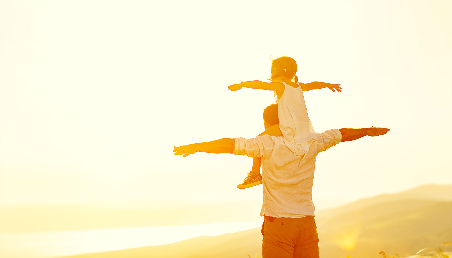 Dad with daughter on shoulders, making airplane wings with arms outstretched