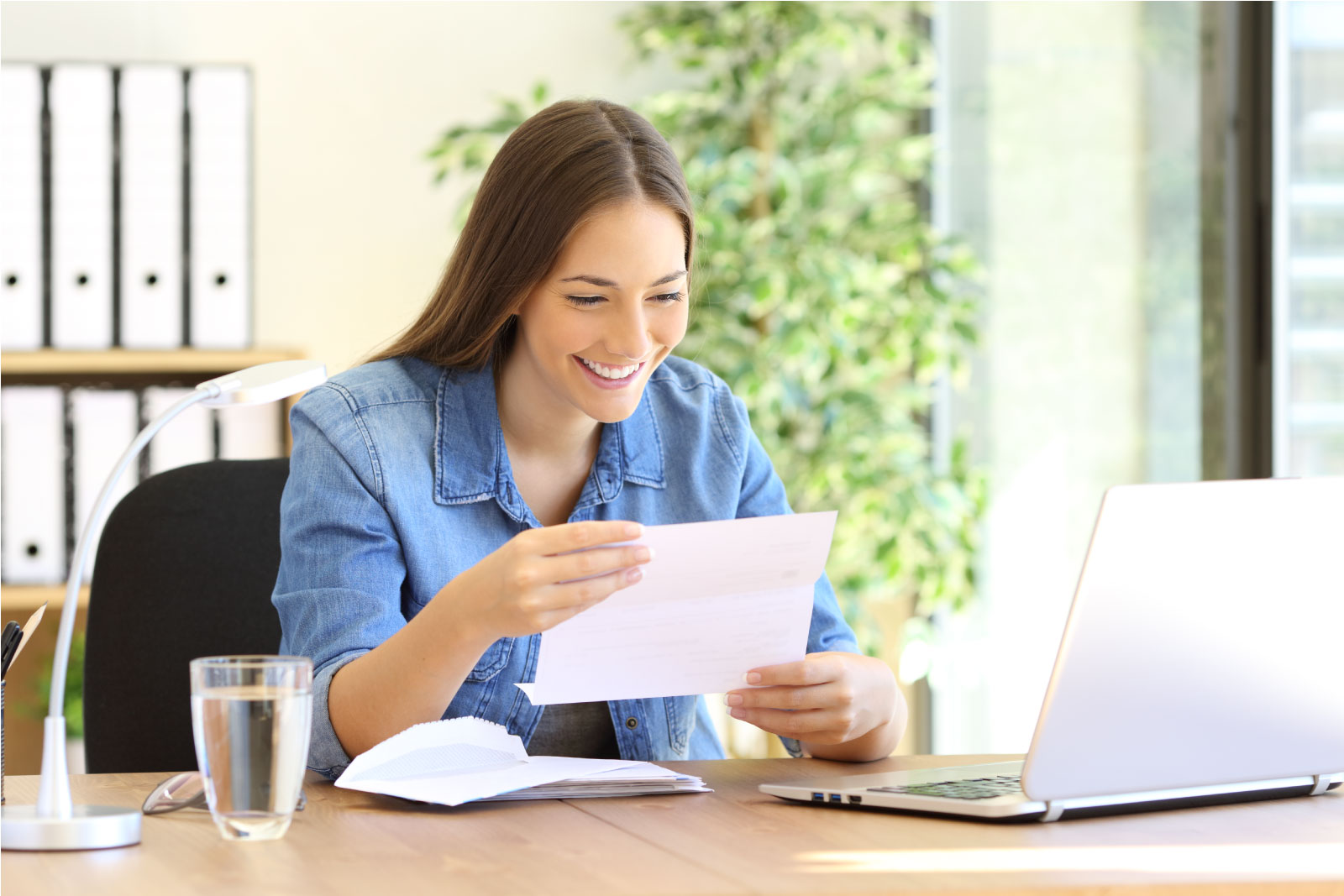 Female entrepreneur reading unclaimed property letter, happy