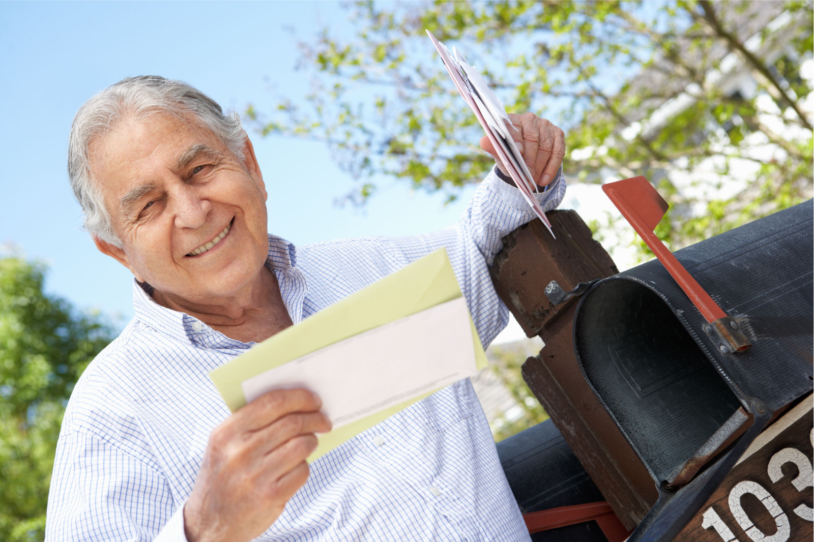 Senior male receiving unclaimed property letter, outdoor mailbox