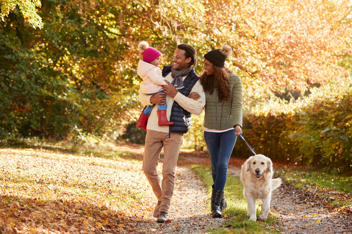 Family with dog walking along outdoor path, smiling