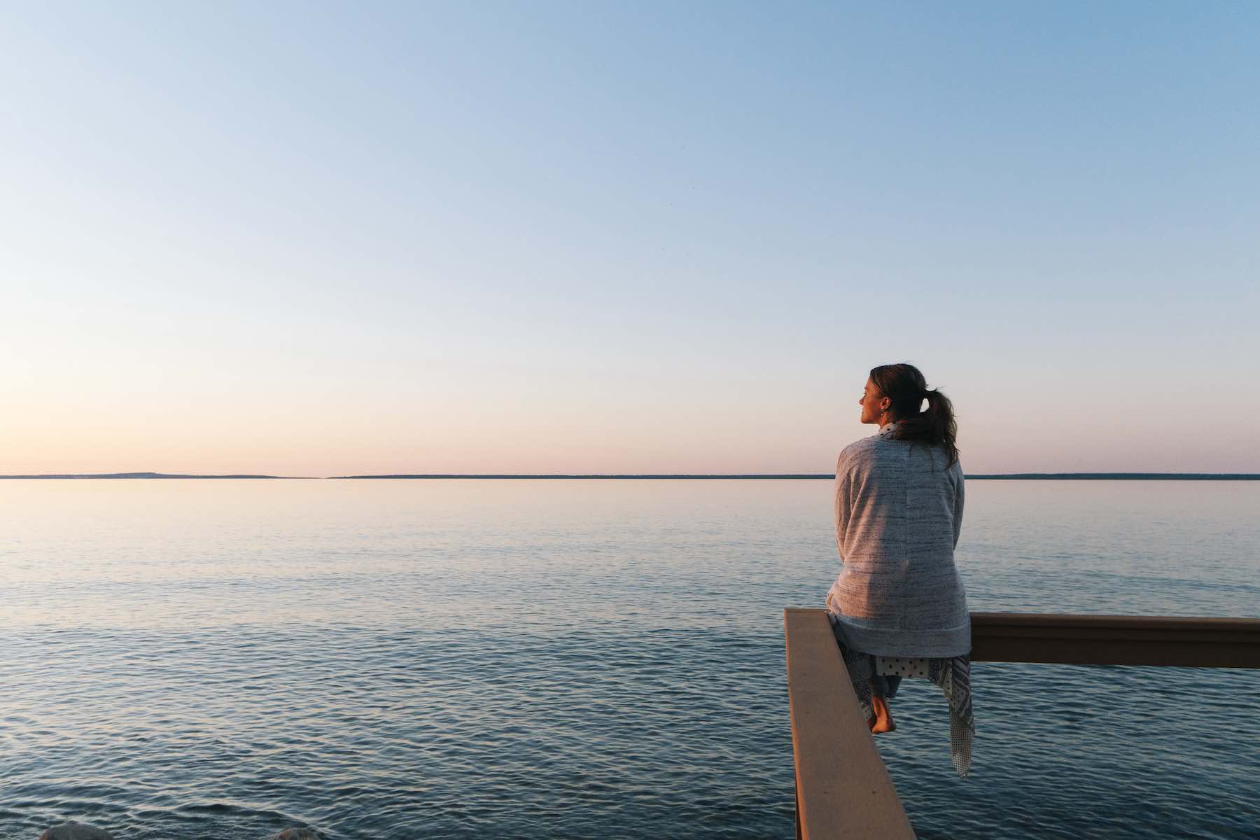 female on pier looking out at water at sunset
