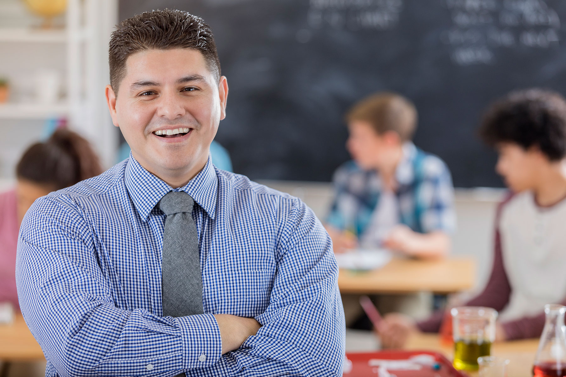 teacher smiling, standing in front of classroom